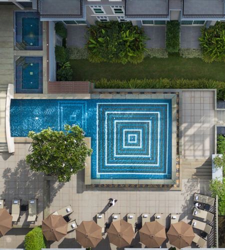 Describe the unique top-down angle, the striking geometric tile design, and the poolside setup while integrating key local search phrases.