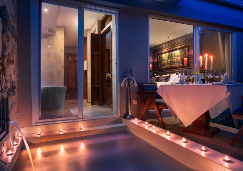 Luxury hotel room at J7 Angkor Hotel featuring a private outdoor plunge pool lit with candles and a romantic candlelit dinner setup on the patio terrace at night.